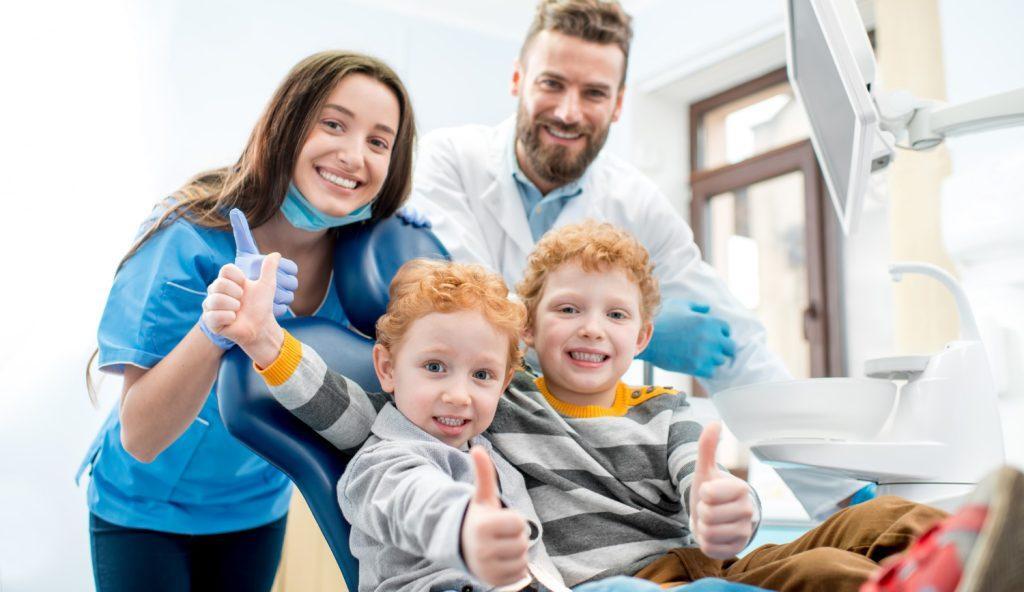 portrait-happy-young-boys-sitting-chair-with-dentist-woman-assistant-dental-office